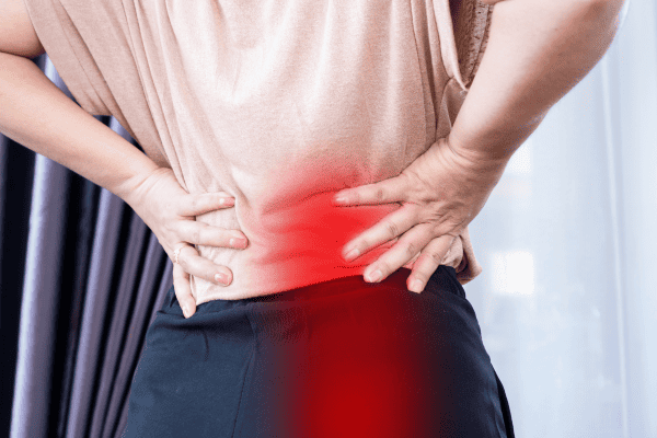 woman with holding lower back and hips with red highlight indicating pain in the right lowerback down to the buttox 